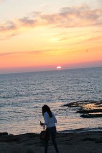 Side view of a man standing on beach at sunset