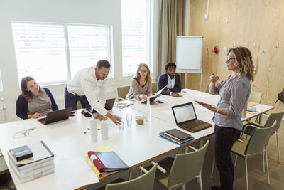 Businesswoman giving presentation to colleagues at conference table in meeting