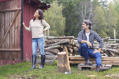 Man looking at woman holding open barn door while sitting by firewood