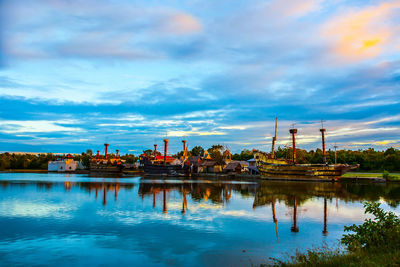 Scenic view of lake by buildings against sky at dusk