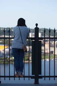 Rear view of woman standing against railing