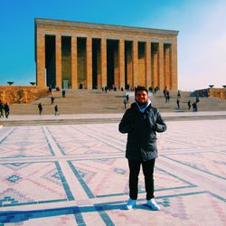 Full length portrait of man standing against building and sky