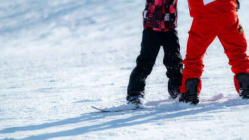 Boy learning to ride snowboard with an instructor