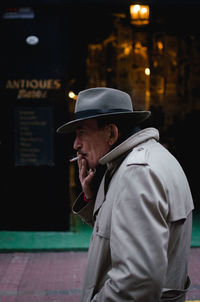 Side view of man wearing hat standing at night