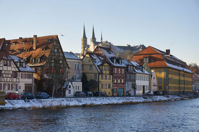 Houses by river against clear sky