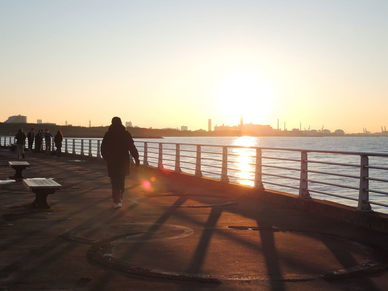 sunset, silhouette, water, sun, lifestyles, leisure activity, orange color, sea, clear sky, standing, sunlight, full length, men, railing, sky, reflection, rear view, person