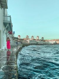 Rear view of woman by swimming pool against sea