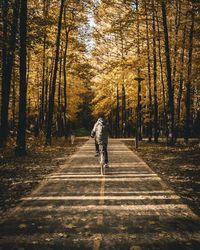 Rear view of man walking on road amidst trees