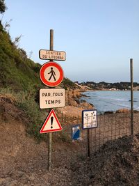 Information sign on road by sea against clear sky