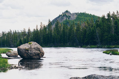 Rocks by lake against sky