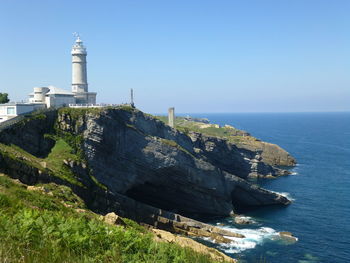 Lighthouse by sea against clear sky