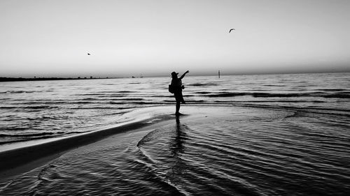 Silhouette woman on beach against sky