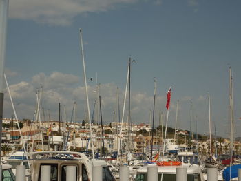 Sailboats moored at harbor against sky