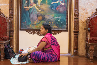 Side view of young woman sitting at home