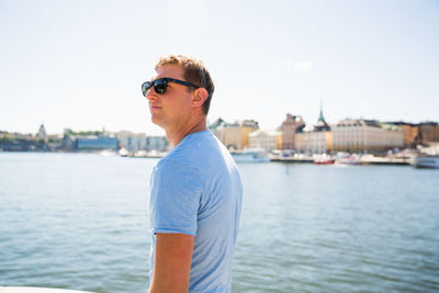 Young man wearing sunglasses standing against sky