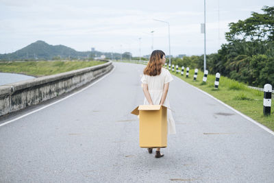 Rear view of woman standing on road