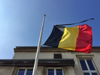 Low angle view of belgium flag waving against building