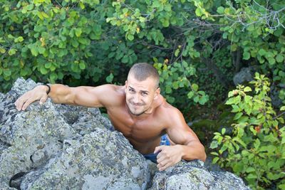 Portrait of shirtless man on rock