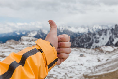 Close-up of hand showing thumbs up against sky