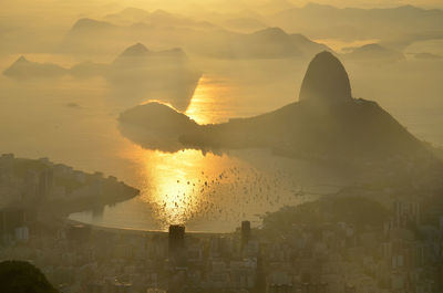 Aerial view of boats in sea by sugarloaf mountain and city during sunrise