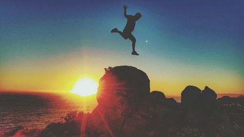 Silhouette of man jumping against sky during sunset