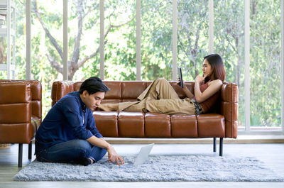 Young woman using phone while sitting on sofa