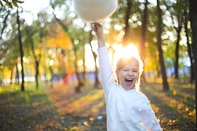 Happy woman with arms raised in park
