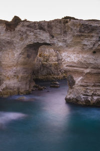 Rock formations by sea against sky