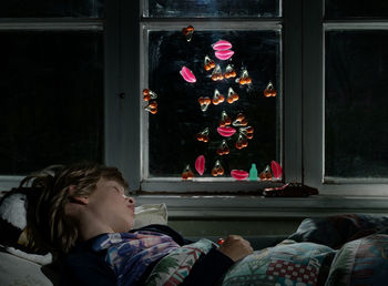 Side view of boy sleeping through a candy window