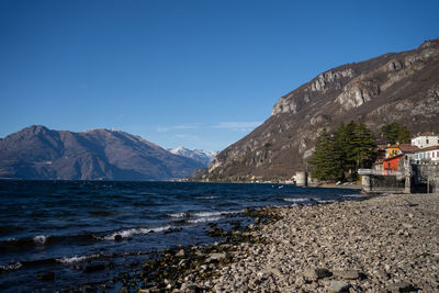 Scenic view of sea and mountains against clear blue sky