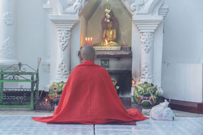 Rear view of man sitting in temple outside building