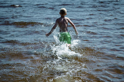 Full length of man splashing water in sea