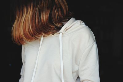 Rear view of woman standing against black background