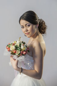 Portrait of woman holding rose against white background