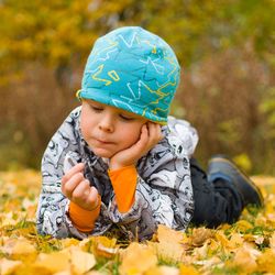 Boy wearing mask in autumn leaves