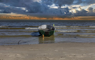 Scenic view of fisherman boat on the beach against sky during sunset