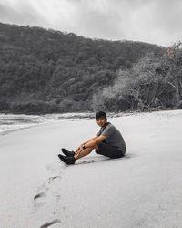 Side view of young man sitting on land