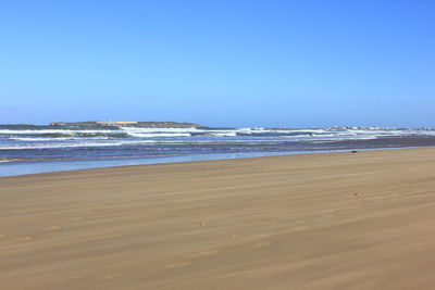 Scenic view of beach against clear blue sky