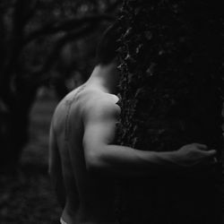 Close-up of shirtless boy on tree trunk