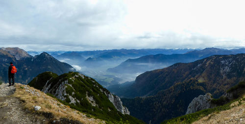 Scenic view of mountains against sky with man standing on rock