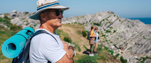 Side view of man wearing sunglasses standing at beach