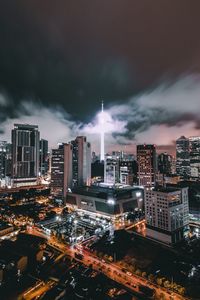 Illuminated cityscape against cloudy sky