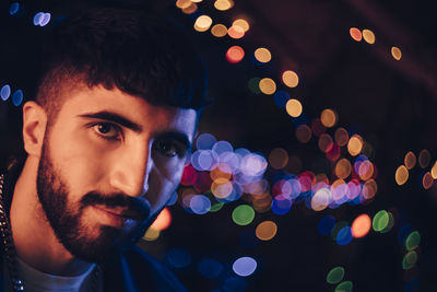 Confident young bearded against colorful lights at restaurant