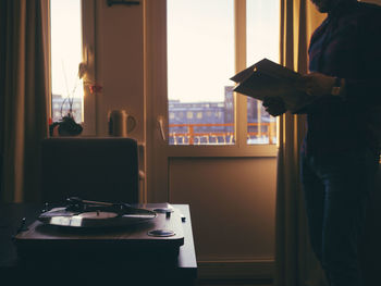 Midsection of man holding book at home