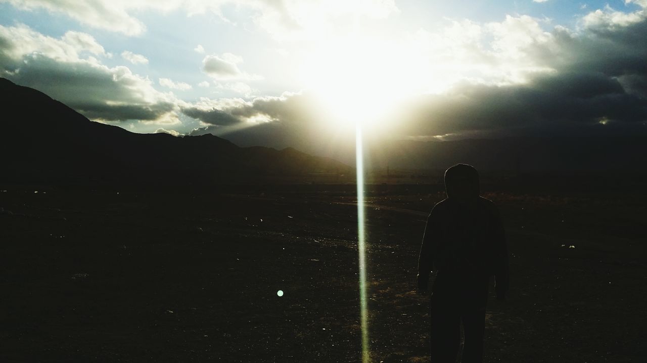 silhouette, sky, sun, lifestyles, leisure activity, men, sunlight, mountain, standing, sunset, sunbeam, rear view, unrecognizable person, beauty in nature, tranquil scene, scenics, tranquility, cloud - sky
