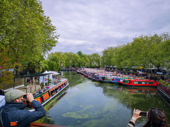 Boats in river by trees against sky