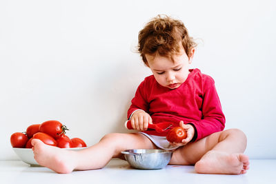 Midsection of man sitting on red table against white background