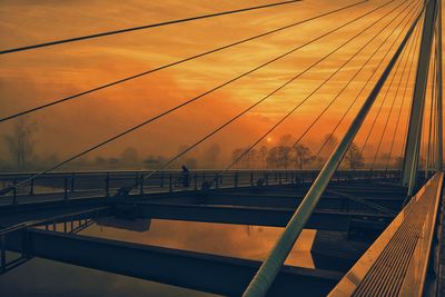 Railroad track on bridge against sky during sunset