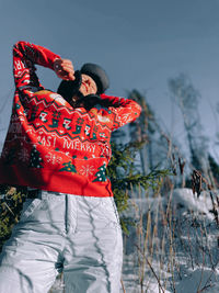 Rear view of woman with arms raised standing on snow