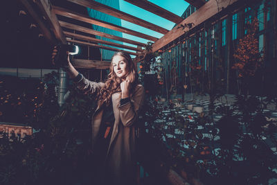 Portrait of young woman holding lighting equipment in plant nursery